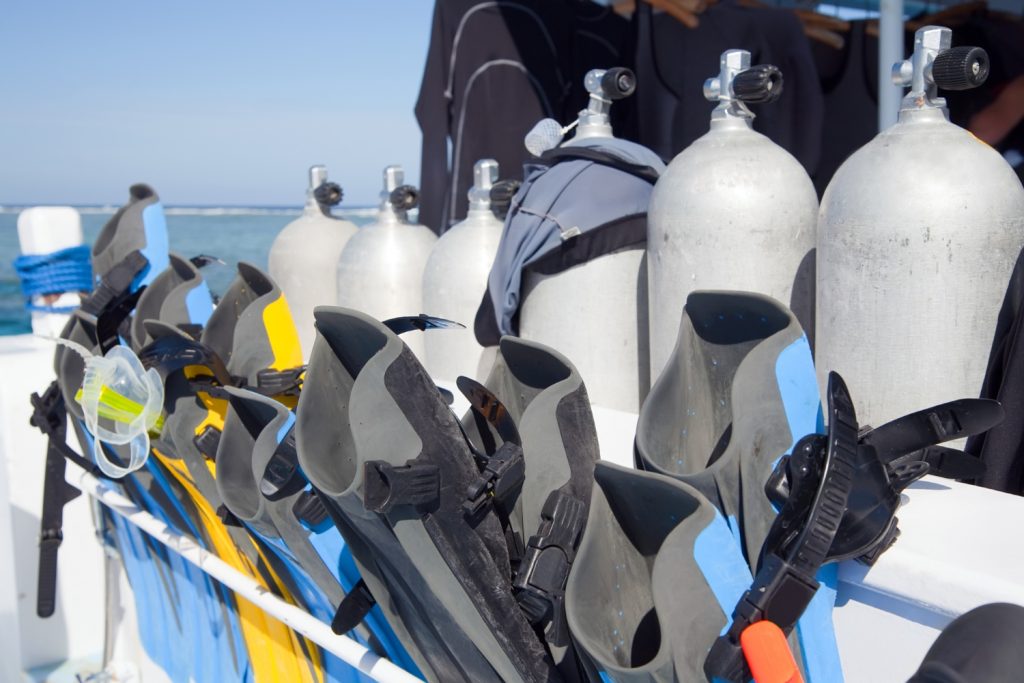 Scuba divers adjusting equipment, preparing to enter water from inflatable boat